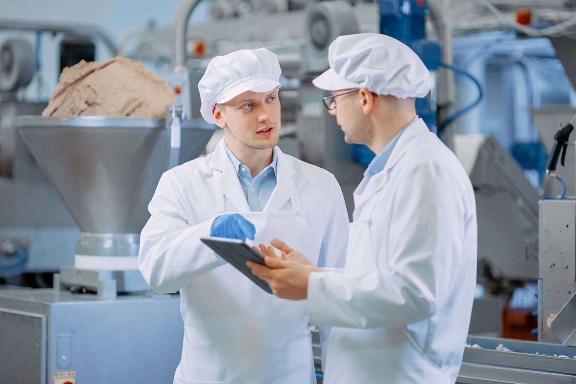 two men discuss iiot findings on tablet in food manufacturing plant